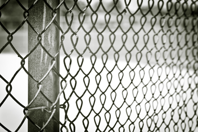 Chain fence perspective of the field where The Cycle Lords ambush the T-Birds while training with Coach Calhoun